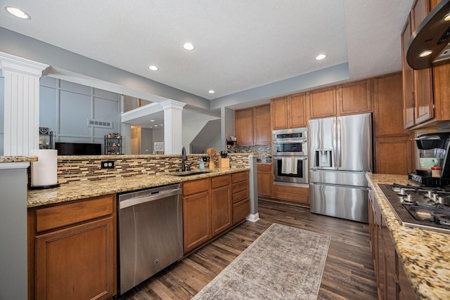 1923 Mallow Ln, Grove City, OH 43123 - kitchen featuring stainless steel appliances, ornate columns, brown cabinets, a sink, and decorative backsplash