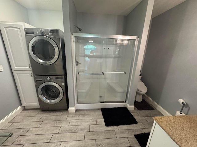 8610 Sadie Thomas Rd NW, Johnstown, OH 43031 - bathroom featuring stacked washer / drying machine, wood finish floors, a stall shower, baseboards, and toilet