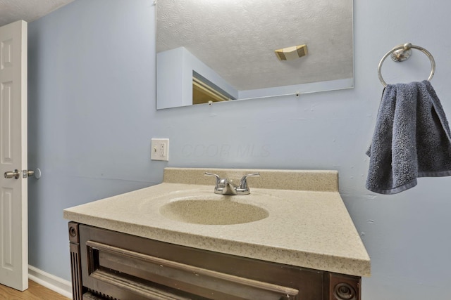 bathroom with a textured ceiling, wood finished floors, and vanity