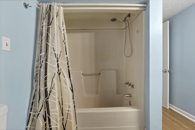full bathroom with baseboards, shower / tub combo, toilet, and wood finished floors