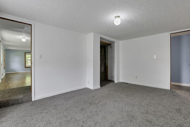 unfurnished room featuring carpet, a textured ceiling, and baseboards