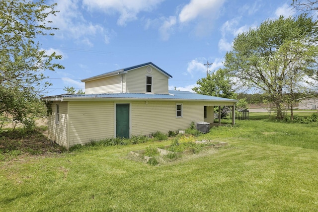 rear view of house with a yard, central air condition unit, and metal roof