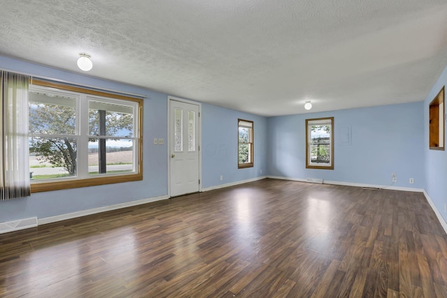 unfurnished living room featuring dark wood finished floors, a textured ceiling, visible vents, and baseboards