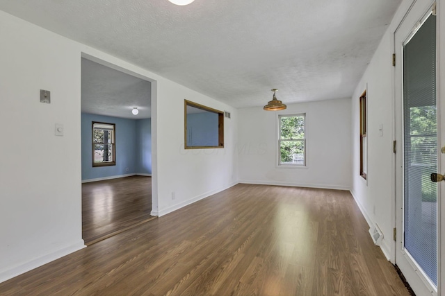 unfurnished room featuring a textured ceiling, dark wood-style flooring, and baseboards