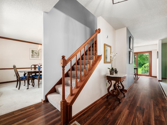 staircase with wood finished floors, a textured ceiling, and baseboards
