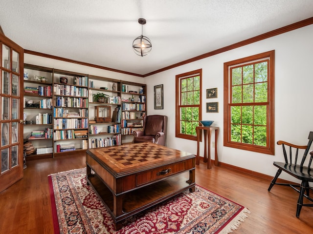 living area with wood finished floors, crown molding, baseboards, and a textured ceiling