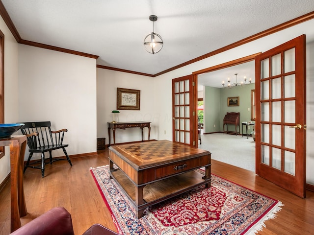home office with wood finished floors, crown molding, a chandelier, baseboards, and french doors