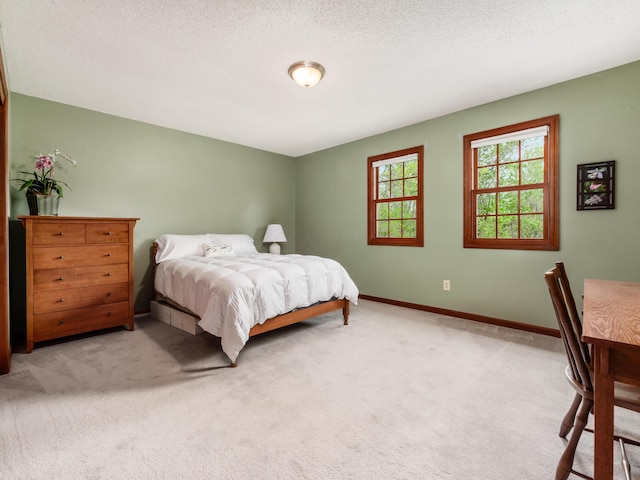 bedroom featuring light colored carpet, baseboards, and a textured ceiling