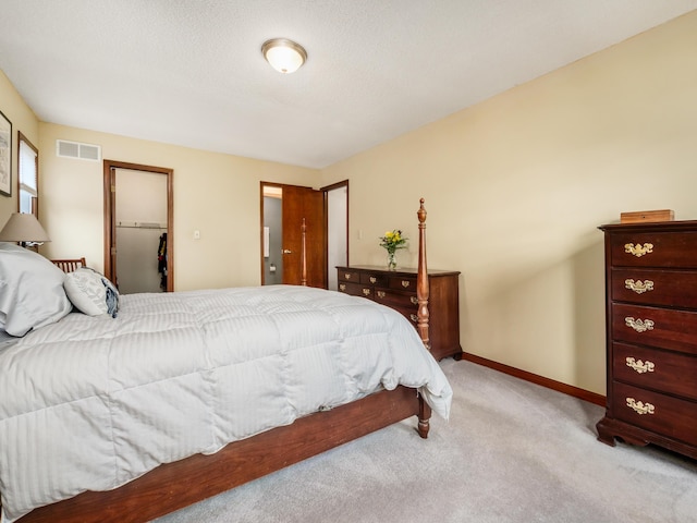 bedroom featuring light carpet, baseboards, and a walk in closet