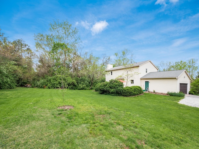 view of green lawn with an attached garage and driveway