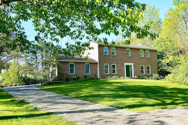 colonial home featuring a front yard and brick siding