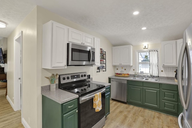 265 E St, Buckeye Lake, OH 43008 - kitchen with appliances with stainless steel finishes, a sink, a textured ceiling, green cabinets, and light wood-type flooring