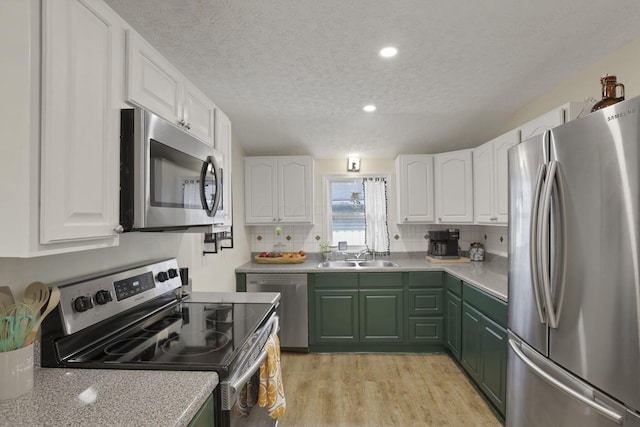 265 E St, Buckeye Lake, OH 43008 - kitchen featuring appliances with stainless steel finishes, a sink, green cabinets, a textured ceiling, and white cabinetry