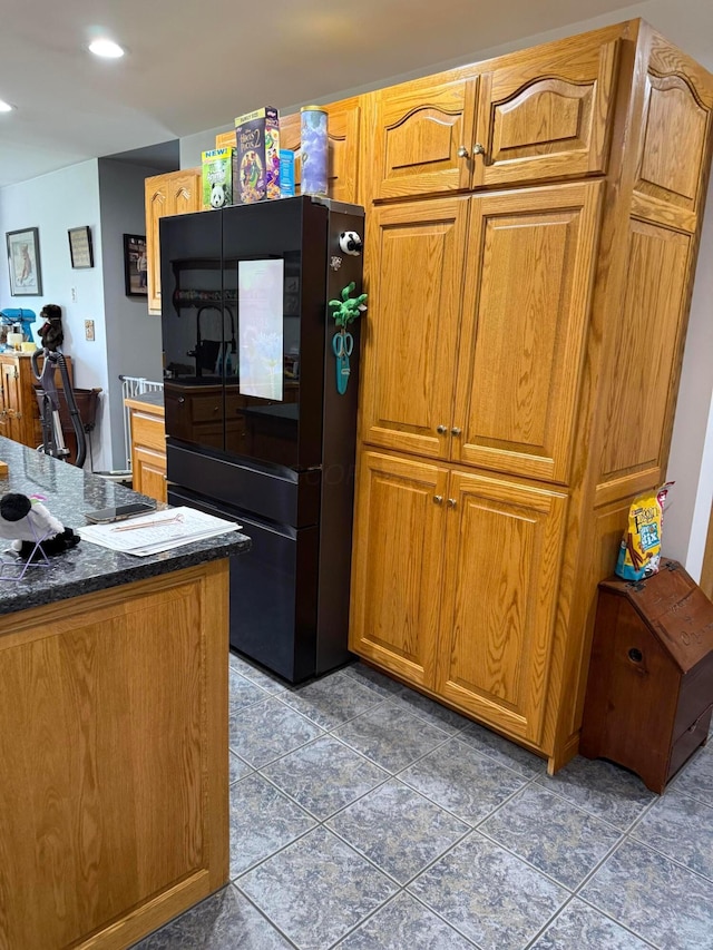 1305 Bald Hill Rd, Zanesville, OH 43701 - kitchen with freestanding refrigerator, tile patterned floors, brown cabinets, dark stone counters, and recessed lighting