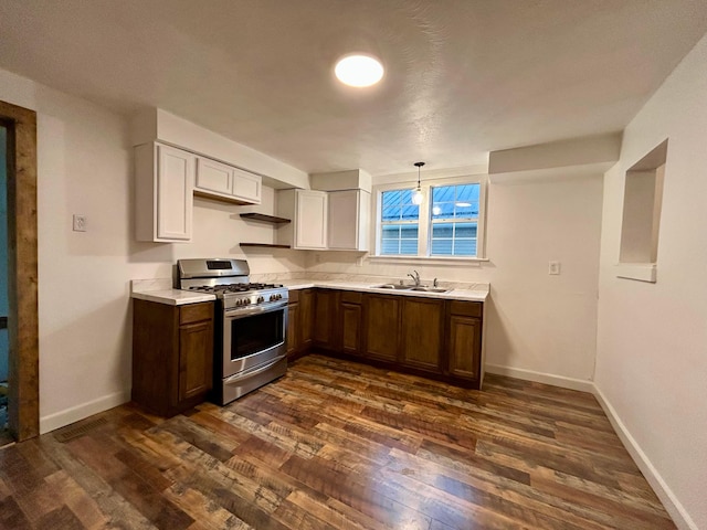 kitchen featuring stainless steel range with gas cooktop, dark wood-style flooring, a sink, and light countertops