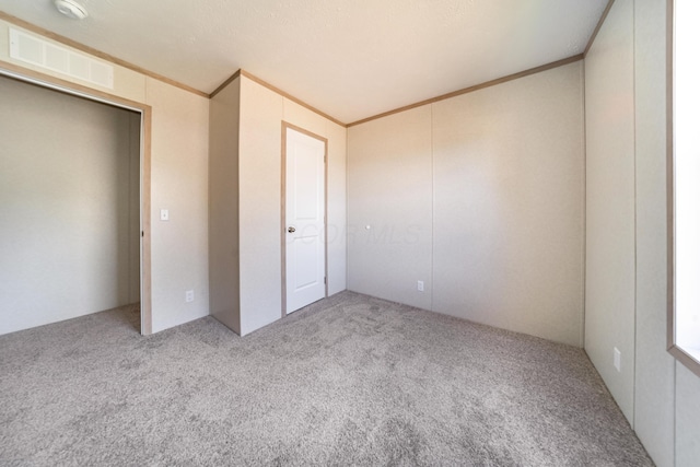 unfurnished bedroom featuring crown molding, carpet floors, and visible vents