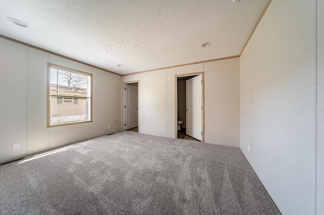 unfurnished bedroom featuring carpet floors, ornamental molding, a textured ceiling, and visible vents