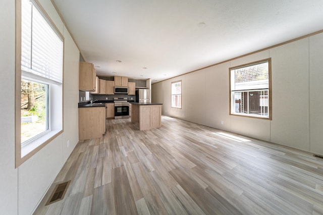 kitchen featuring visible vents, light brown cabinets, dark countertops, light wood-type flooring, and appliances with stainless steel finishes