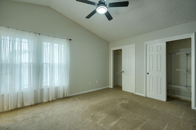 unfurnished bedroom with two closets, carpet, lofted ceiling, baseboards, and ceiling fan