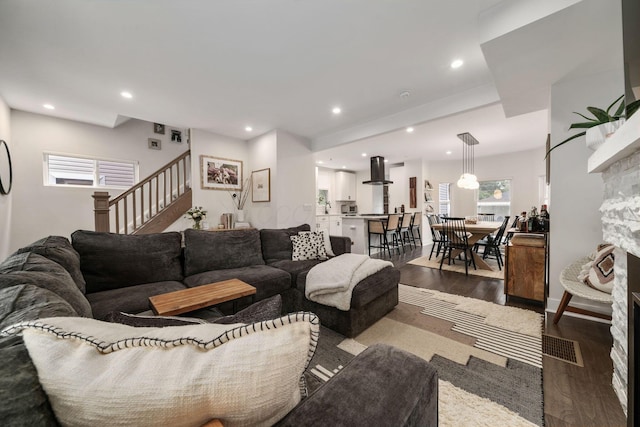living area with stairs, recessed lighting, dark wood-style floors, and a fireplace
