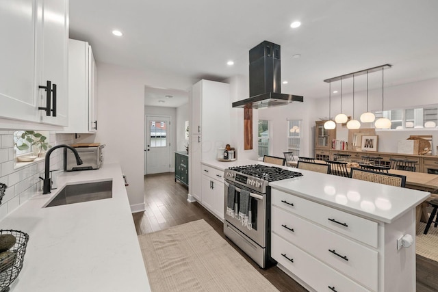 kitchen with stainless steel gas range, a sink, light countertops, island range hood, and backsplash