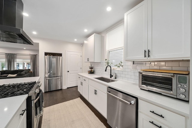 kitchen featuring wall chimney range hood, appliances with stainless steel finishes, a sink, a toaster, and backsplash