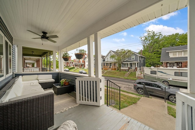 wooden terrace featuring a porch, a ceiling fan, an outdoor hangout area, and a residential view