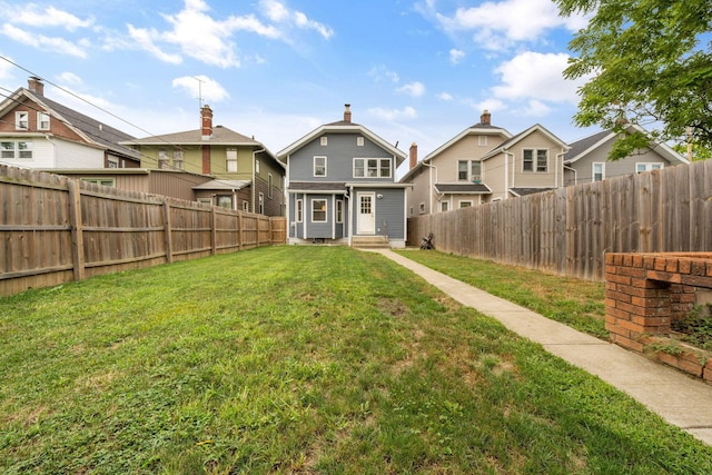 rear view of property with a lawn, a fenced backyard, and entry steps