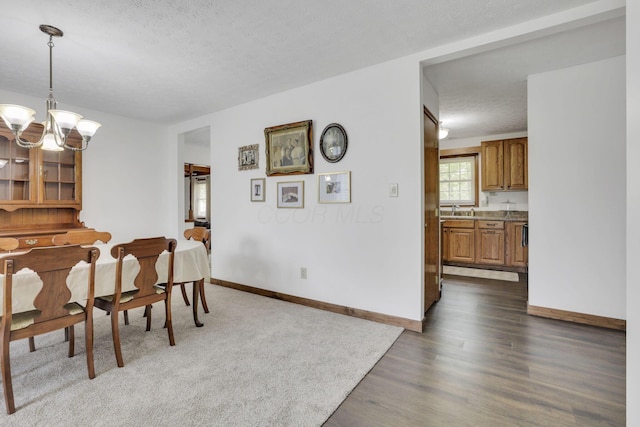 dining room with baseboards, a textured ceiling, dark wood-style flooring, and a chandelier