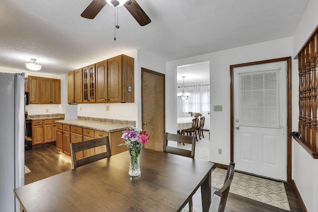 dining area with baseboards, dark wood-type flooring, and ceiling fan with notable chandelier
