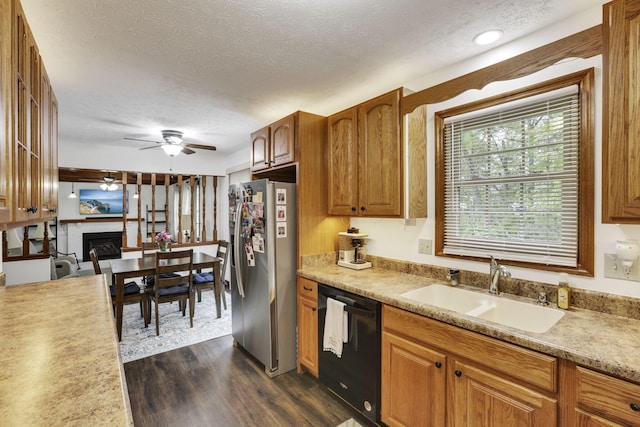 kitchen featuring a fireplace, black dishwasher, stainless steel refrigerator with ice dispenser, dark wood-type flooring, and a sink