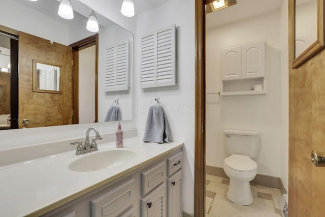 bathroom with vanity, baseboards, and toilet