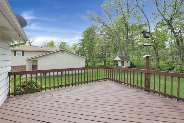 wooden terrace featuring a yard, an outbuilding, and a storage shed