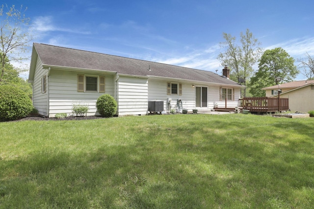 back of property with a chimney, a lawn, central AC unit, a deck, and roof with shingles