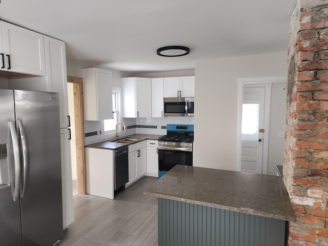 kitchen with dark countertops, plenty of natural light, appliances with stainless steel finishes, and a sink