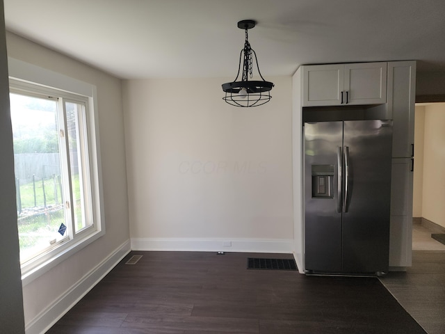 unfurnished dining area with dark wood-style flooring, baseboards, and visible vents