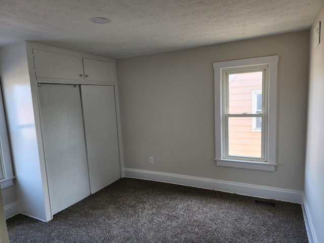 unfurnished bedroom with baseboards, multiple windows, and dark carpet