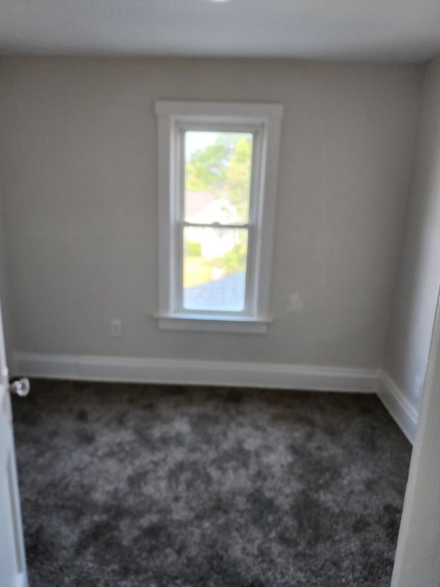 empty room featuring baseboards and carpet
