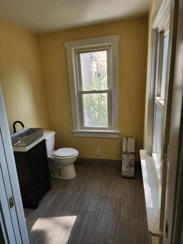 half bathroom with toilet, baseboards, and a sink