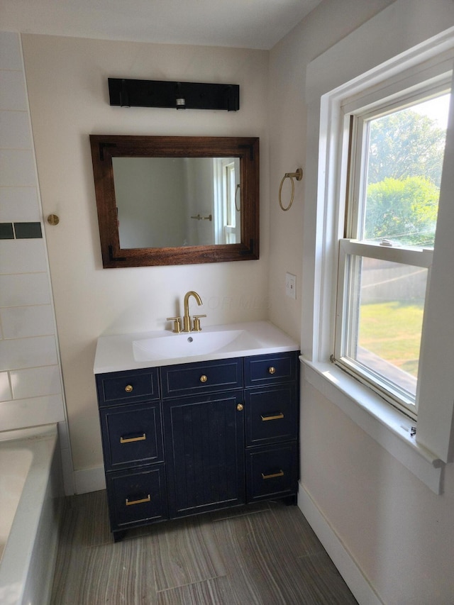 bathroom featuring baseboards, vanity, and a bath