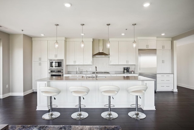 kitchen featuring wall chimney exhaust hood, built in appliances, recessed lighting, baseboards, and light countertops