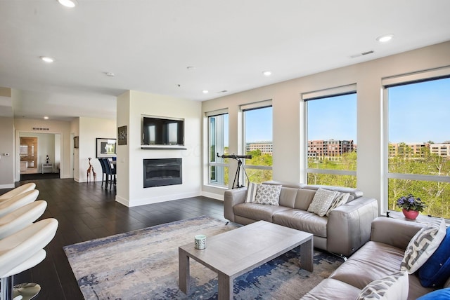 living area with baseboards, dark wood-type flooring, recessed lighting, and a glass covered fireplace