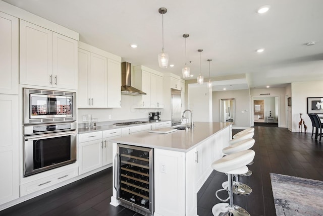 kitchen with appliances with stainless steel finishes, wine cooler, wall chimney exhaust hood, dark wood-style flooring, and recessed lighting