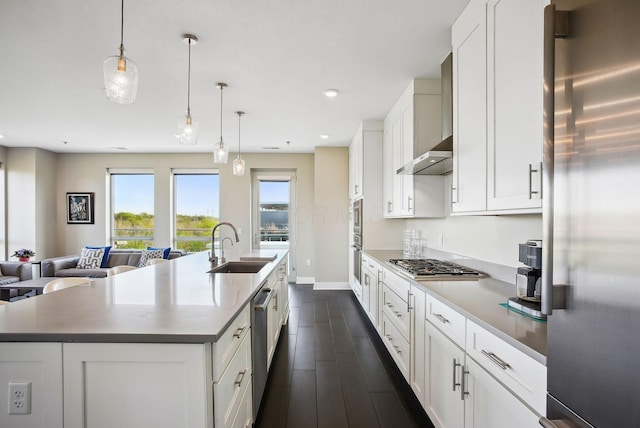 kitchen featuring appliances with stainless steel finishes, a sink, open floor plan, white cabinetry, and a center island with sink