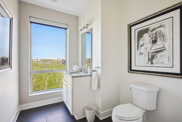 bathroom with toilet, vanity, and baseboards