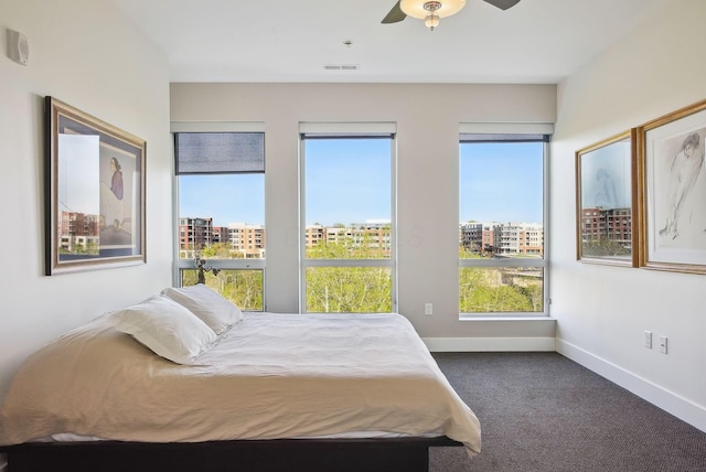 bedroom featuring dark carpet, baseboards, multiple windows, and ceiling fan