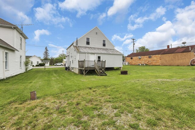rear view of house featuring a wooden deck, a yard, and metal roof