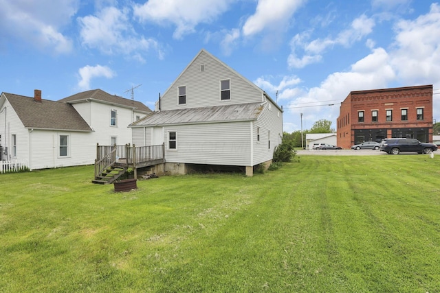 back of property with a lawn, a deck, and metal roof