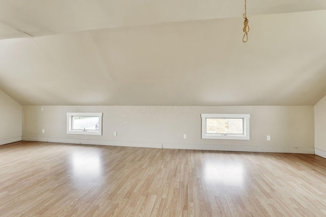 additional living space featuring light wood finished floors, vaulted ceiling, and baseboards