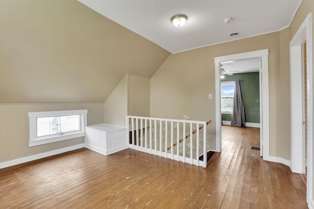 additional living space with wood-type flooring, plenty of natural light, baseboards, a ceiling fan, and lofted ceiling